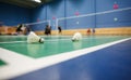 badminton courts with players competing; shuttlecocks in the foreground