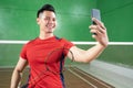 Badminton player in red holding racket while taking selfie