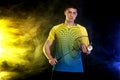 Badminton player in sportswear with racket and shuttlecock on black background with color smoke. Olympic game. Royalty Free Stock Photo
