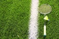 Badminton racket, yellow plastic training shuttlecock on the green grass near the white marking of the court, vertically Royalty Free Stock Photo