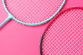 Badminton rackets on a bright pink background. Royalty Free Stock Photo