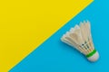 Badminton shuttlecock or birdie on a solid bright blue and yellow flat lay background symbolizing sports and activity with copy Royalty Free Stock Photo