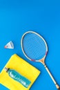 Badminton training concept. Badminton racket, shuttlecock, sport drink and towel on blue background top view copy space