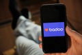 Badoo application on the smartphone in mans hand. Man laying and using application for dating and meeting. Social