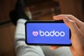 Badoo application on the smartphone in mans hand. Man laying and using application for dating and meeting. Social