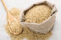 Bag burlap with brown rice and wooden spoon on table Royalty Free Stock Photo