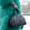 Bag close-up in female hands. Stylish modern and feminine image, style. Girl in a green coat with a black bag and gloves