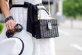 Bag closeup in female hands. Black and white image style. Women`s accessories: watches, glasses, rings and bracelets.