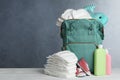 Bag with diapers and baby accessories on white wooden table against grey background. Space for text