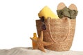 Bag with different beach objects on sand against white