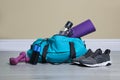 Bag with different sports equipment on wooden floor indoors