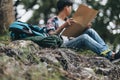 Bag on the ground and Lost hiker with backpack checks map to find directions near the river in the forest. hiking and adventure Royalty Free Stock Photo