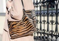 Bag in leopard print close-up. large shopping leather handbag in female hands. Woman walking in the city. Girl in a beige coat