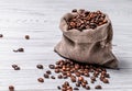 Bag made from burlap cloth with coffee beans and some grains lying near it on the light background Royalty Free Stock Photo