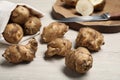 Bag and many Jerusalem artichokes with knife on white wooden table Royalty Free Stock Photo