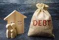 A bag of money with the word Debt and the family standing near the house. The concept of debt for housing. Mortgage. Real estate,