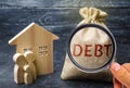 A bag of money with the word Debt and the family standing near the house. The concept of debt for housing. Mortgage. Real estate,