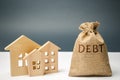 A bag of money with the word Debt and wooden houses. The concept of debt for housing. Mortgage. Real estate, home savings, loans