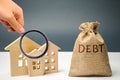 A bag of money with the word Debt and wooden houses. The concept of debt for housing. Mortgage. Real estate, home savings, loans