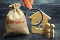 A bag with money and the word Mortgage and a wooden house. The accumulation of money to pay interest rates on mortgages. Buying a Royalty Free Stock Photo