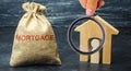 A bag with money and the word Mortgage and a wooden house with a tenant. The accumulation of money to pay interest rates on Royalty Free Stock Photo