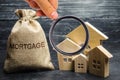 A bag with money and the word Mortgage and a wooden houses. The accumulation of money to pay interest rates on mortgages. Buying a Royalty Free Stock Photo