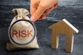 A bag with money and the word risk and a wooden house. Buying property on credit. The concept of financial risk. Loss of housing