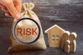 A bag with money and the word risk and a wooden house. Buying property on credit. The concept of financial risk. Loss of housing