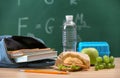 Bag with notebooks and appetizing food on table in classroom Royalty Free Stock Photo