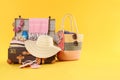 Bag and open vintage suitcase with beach objects packed for summer vacation on orange background Royalty Free Stock Photo