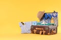 Bag and packed vintage suitcase with beach objects on orange background, space for text. Summer vacation