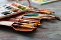 Bag with paint brushes and watercolors on wooden table Royalty Free Stock Photo