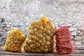 Bag Potatoes and carrots in the yellow and red net products vegetables young , against an old grey stone wall background