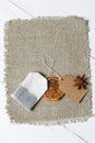 A bag of tea, anise and slices of dried tangerines. Lying on a piece of linen. Against the background of white painted boards