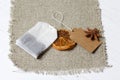 A bag of tea, anise and slices of dried tangerines. Lying on a piece of linen. Against the background of white painted boards