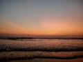 Baga beach with layered ocean waves during a colorful sunset.