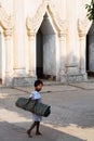 Bagan, Myanmar - March 2019: Child carrying rolled bamboo mat in Bagan