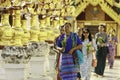 A group of Burmese people are carrying flowers to pay respect to Buddha images in a temple.