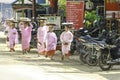 Young Burmese novice girls puts a basket on her head and asks to donate food in the market.