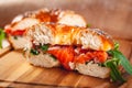 Bagel with cream cheese, smoked salmon and arugula salad cut in half on wooden board. Royalty Free Stock Photo