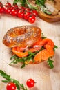 Bagel with cream cheese, smoked salmon and arugula salad on wooden board. Royalty Free Stock Photo