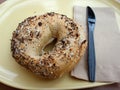 Bagel and Plastic Knife on a yellow plate