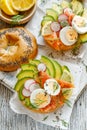 Bagel sandwich with smoked salmon, avocado, boiled eggs, radish, lemon and fresh dill on a wooden table