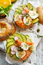 Bagel sandwich with smoked salmon, avocado, boiled eggs, radish, lemon and fresh dill on a wooden table