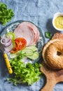 Bagel sandwich with turkey ham, vegetables and green salad on a blue background, top view, Flat lay. Healthy food Royalty Free Stock Photo