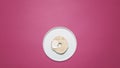 Bagel with cream cheese on a white plate on pink
