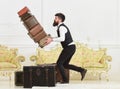 Baggage insurance concept. Porter, butler accidentally stumbled, dropping pile of vintage suitcases. Man with beard and Royalty Free Stock Photo