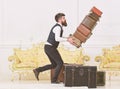 Baggage insurance concept. Porter, butler accidentally stumbled, dropping pile of vintage suitcases. Man with beard and