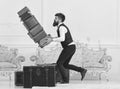 Baggage insurance concept. Porter, butler accidentally stumbled, dropping pile of vintage suitcases. Man with beard and Royalty Free Stock Photo