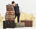 Baggage and relocation concept. Macho elegant on tired face, exhausted at end of packing, leans on pile of vintage